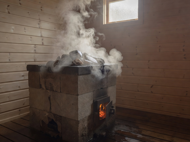 Höyryävä puukiuas saunassa